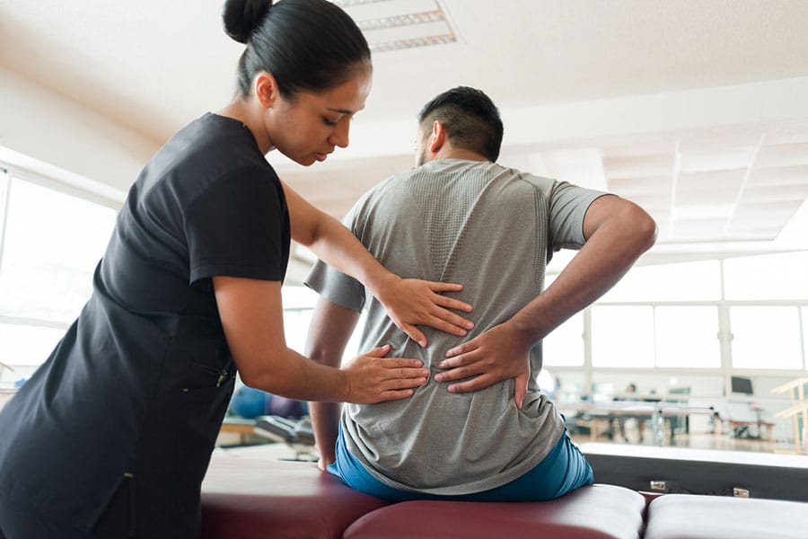 physical therapist massaging mans back