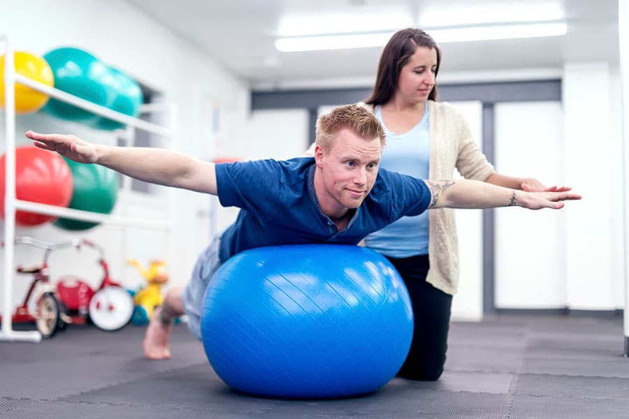 Man performing physical therapy on ball